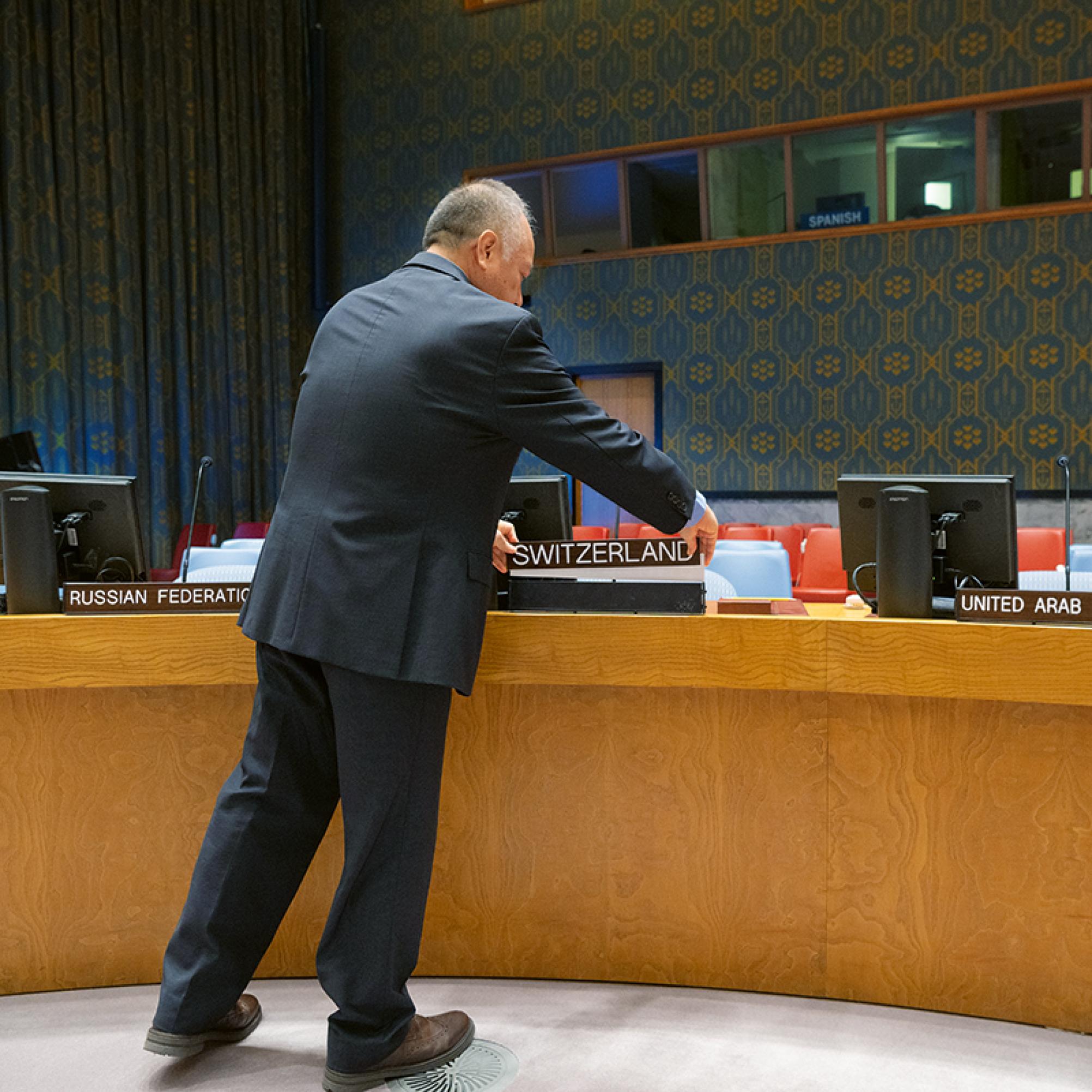La foto mostra un uomo che prepara il seggio della Svizzera al Consiglio di Sicurezza dell'ONU.