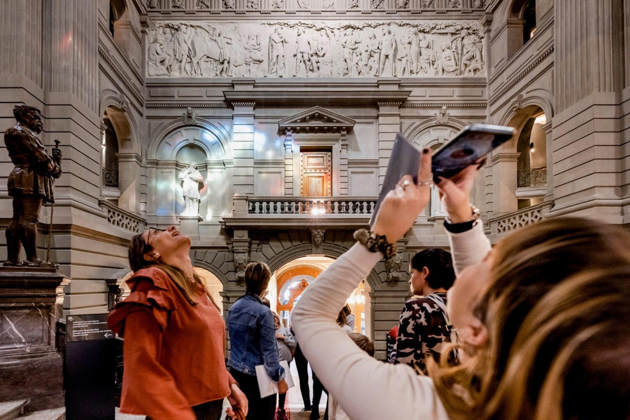 Das Bild zeigt Menschen in der Eingangshalle des Parlamentsgebäudes: Die meisten blicken nach oben, um die Kuppel anzuschauen.